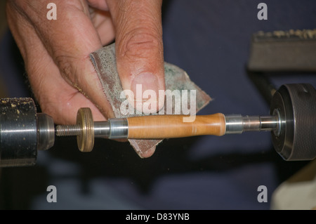 Usando carta vetrata su un tornio per la forma di una penna in legno Foto Stock