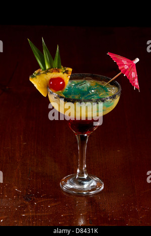 Bella tropical cocktail servito in un bicchiere Margarita con sale nero sul cerchio e una fetta di ananas con una ciliegia in esso Foto Stock