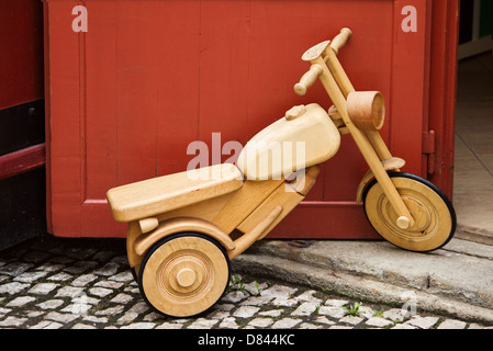 Biciclette giocattolo di legno sorge accanto alla porta rossa Foto Stock