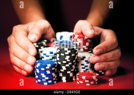 L'uomo le mani si muovono le vincite casino chips sulla tabella rossa. Foto Stock