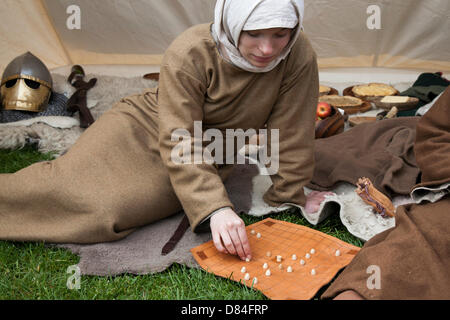 Giocando a Tafl, Hnefatafl una famiglia di antichi giochi da tavolo con dadi a strategia germanica e celtica giocati su un tabellone a scacchi o a reticolo con due eserciti di numeri irregolari. Gioco da tavolo al primo giorno medievale di Ormskirk, dove il gruppo di rievocazioni Historia Normannis del XII secolo riporta le persone indietro nel tempo, con la vita quotidiana del XII secolo in occasione dell'evento inaugurale del Parco dell'Incoronazione. Historia Normanni è un gruppo di rievocazioni del XII secolo, che si concentra principalmente sugli eventi tra il regno di Enrico i e il re Giovanni. Foto Stock