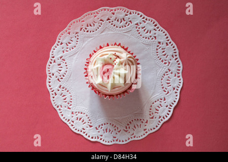 Fragole e panna cupcake su bianco centrino impostato su sfondo rosa Foto Stock