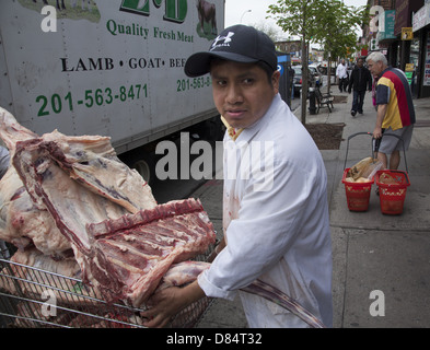 L'uomo offre carni fresche per una carne halal store sulla Chiesa Avenue nel quartiere di Kensington, Brooklyn, New York. Foto Stock