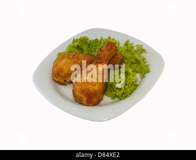 Pollo fritto pezzi su una piastra con lattuga. Prese su di un foglio di plastica bianca. Foto Stock