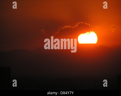 Questa fotografia cattura un tramonto a Tokyo, Giappone, scattato il 2 ottobre 2003. L'immagine mostra i colori vivaci del cielo mentre il sole tramonta sulla città, con lo skyline di Tokyo in primo piano. Foto Stock