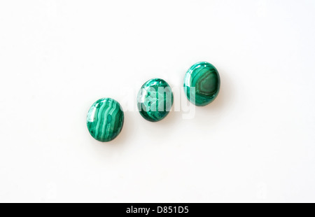 3 di forma ovale di gemme di malachite, isolata su uno sfondo luminoso. Si tratta di un carbonato di rame Idrossido nota minerale con la sua fascia verde Foto Stock
