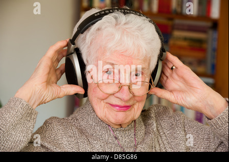 Un'anziana donna che indossa orecchio esterno cuffie Foto Stock