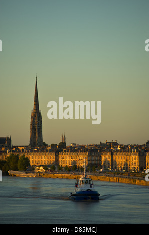 Un rimorchiatore sul fiume Garonna a Bordeaux durante l'alba, Basilica di San Michele è sullo sfondo Foto Stock