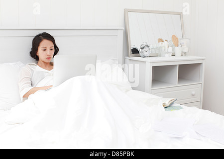 Malati giovane donna studiare a letto. Foto Stock