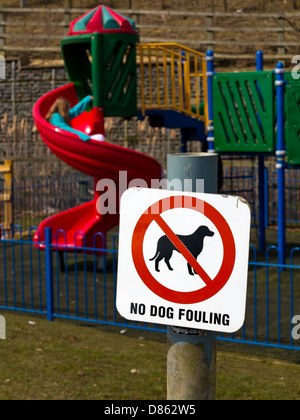 Nessun cane segno di sporcamento con bambini che giocano nel parco giochi in background England Regno Unito Foto Stock