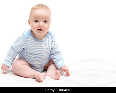 Bambino seduto sul letto bianco Foto Stock