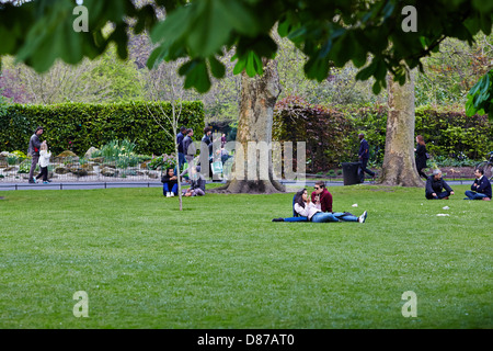 Giovani sedersi e rilassarsi in una giornata di sole in St Stephens Green Park, Dublin, Repubblica di Irlanda Foto Stock