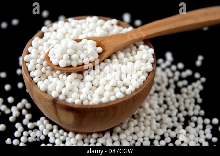 Perle di tapioca in piccola ciotola di legno su sfondo nero Foto Stock