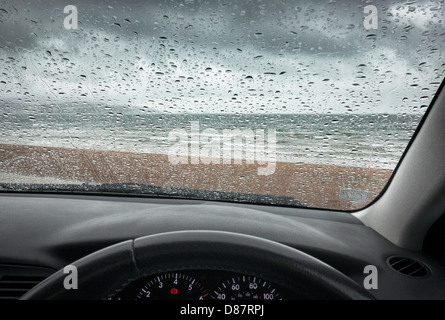 Spiaggia britannica sul mare sotto la pioggia in una giornata di pioggia attraverso il parabrezza/parabrezza dell'auto Foto Stock