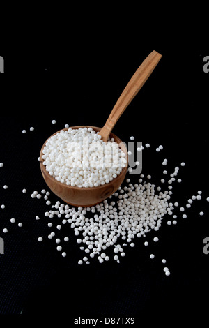 Perle di tapioca in piccola ciotola di legno su sfondo nero Foto Stock