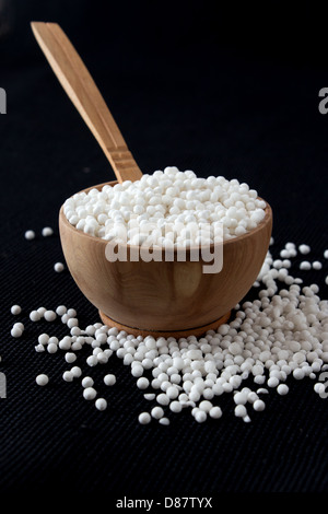 Perle di tapioca in piccola ciotola di legno su sfondo nero Foto Stock