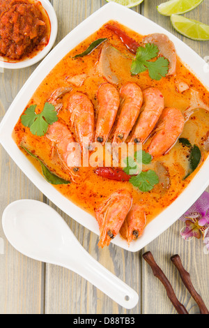 Tom Yum Nam Khon - cremosa zuppa tailandese con gamberi e funghi guarnita con il coriandolo e servite con spicchi di lime. Foto Stock