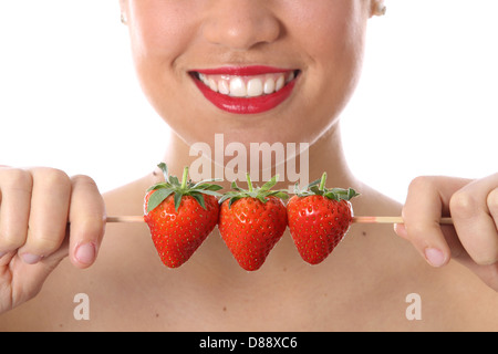 Attraente giovane donna azienda mangiare fresche dolci mature succose fragole isolata contro uno sfondo bianco Foto Stock