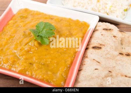 Tarka Dal - giallo indiano split pea curry guarnita con coriandolo e servito con riso pilaf e chapatis. Foto Stock