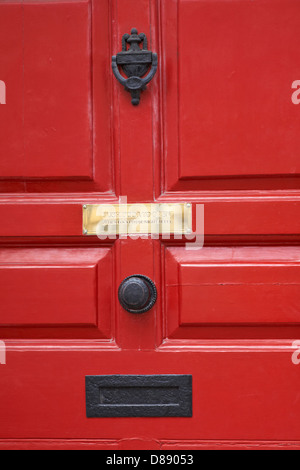 Spingere la porta per aprirla e, una volta chiusa, utilizzare la campana notturna sulla placca della porta con i mobili sulla porta rossa a Bath, Somerset UK in aprile Foto Stock