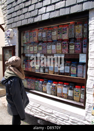 Giovane donna guardando nella finestra di un dolce tradizionale shop, Polperro, Cornwall, Regno Unito 2013 Foto Stock