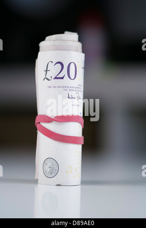 Un rotolo di venti pound note su una tabella. Foto Stock