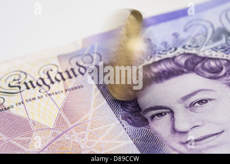 Una libbra di moneta che ruota su una ventina di pound nota. Foto Stock