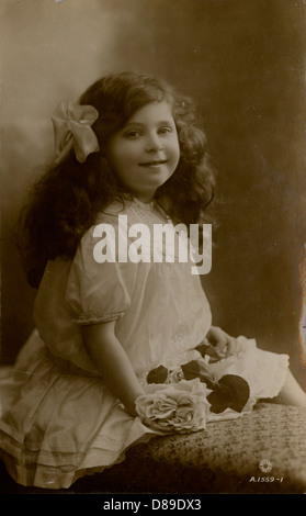 Bambina in abito bianco frilly con rose 1915 Foto Stock