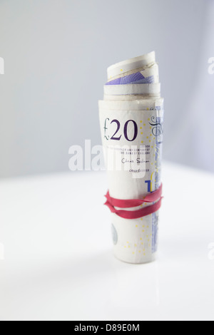 Un rotolo di venti pound note su una tabella. Foto Stock