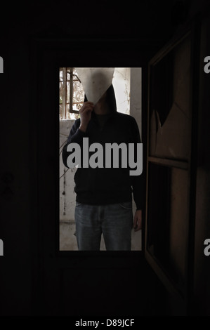 Vetro rotto e uomo in possesso di un pezzo di vetro in casa abbandonata. Foto Stock