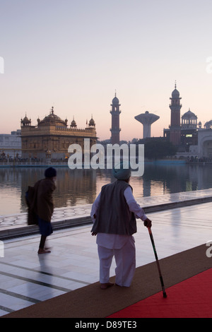 India, Punjab, Amritsar. Tempio d'oro uomo anziano in tradizionale costume Sikh camminare al complesso Foto Stock