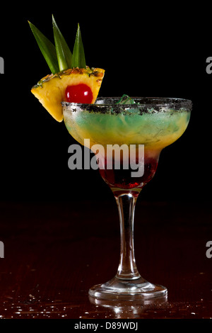 Bella tropical cocktail servito in un bicchiere Margarita con sale nero sul cerchio e una fetta di ananas con una ciliegia in esso Foto Stock