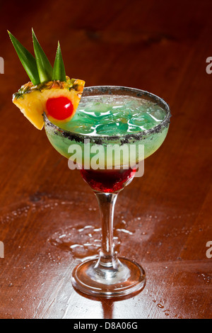 Bella tropical cocktail servito in un bicchiere Margarita con sale nero sul cerchio e una fetta di ananas con una ciliegia in esso Foto Stock