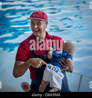 Il comico di fare divertire con un bimbo piccolo con indossare pantaloni corti con un logo Italia, Italia Foto Stock