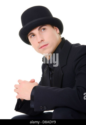 Giovane uomo attraente in abito nero e il cappello è guardando in alto isolato su sfondo bianco Foto Stock