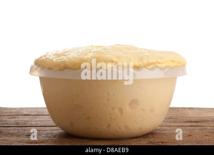 In aumento la pasta lievitata in ciotola sul tavolo di legno Foto Stock