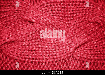 Un primo piano di un motivo a maglia rosso che mostra l'intricata tessitura del filato. Questo motivo a maglia testurizzata viene spesso utilizzato in maglioni, sciarpe e altri capi a maglia per un look caldo e di stile. Foto Stock