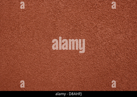 La ruvida consistenza di stucco di terracotta è evidente su questa parete, mostrando i toni caldi e terrosi tipici di questo materiale. Lo stucco in terracotta è spesso usato nell'architettura in stile mediterraneo e aggiunge un'atmosfera rustica e senza tempo agli edifici. Foto Stock