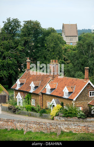 Red Brick cottages con finestre dormer e Giardini e Chiesa di San Lorenzo nel villaggio di Castle Rising, Norfolk, Inghilterra Foto Stock