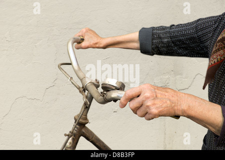 Vecchio mani tenendo il manubrio di una bicicletta. Foto Stock