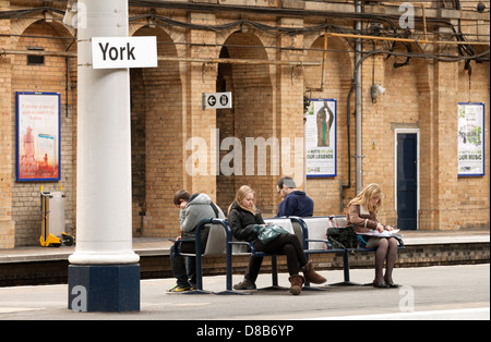 I passeggeri di persone in attesa di un treno sulla piattaforma, la stazione ferroviaria di York, Yorkshire Regno Unito Foto Stock