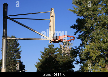 Una vista laterale di un canestro da basket, che mostra il bordo, la rete e il tabellone. Questo angolo mette in risalto i componenti del cerchio e il design del campo da basket, sottolineando l'attrezzatura sportiva. Foto Stock
