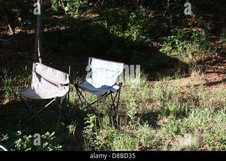 Due sedie da prato vuote posizionate su un'erba soleggiata, perfette per rilassarsi in una giornata calda. Le sedie sono allestite per godersi la giornata luminosa e limpida, con la luce del sole che proietta ombre sull'erba. Foto Stock