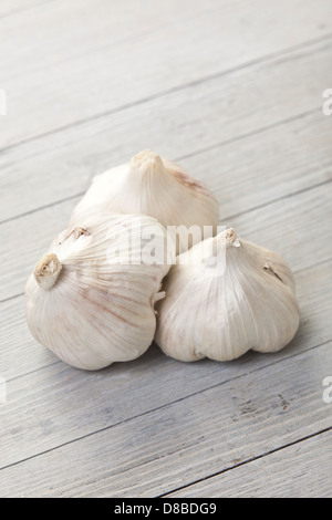 Tre aglio fresco lampadine su un rustico di superficie di legno. Foto Stock