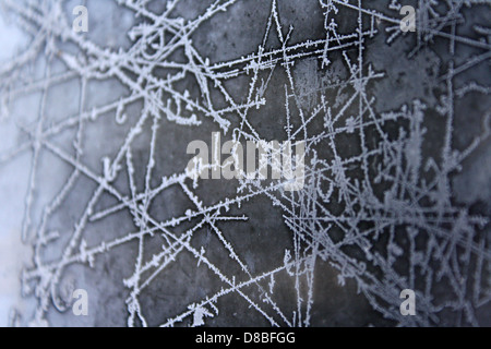 Motivi di ghiaccio intricati decorano la superficie di una finestra congelata. Il gelo forma un design delicato ed esclusivo a causa delle variazioni di temperatura e dell'umidità, creando texture bellissime in condizioni climatiche fredde. Foto Stock