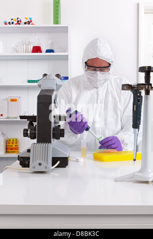 Un tecnico di laboratorio in abbigliamento sterile utilizzando una pipetta Foto Stock