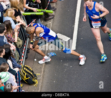 Runner atleta concorrente di fermarsi per allungare le gambe durante 2013 maratona di Londra Inghilterra Europa Foto Stock