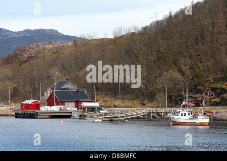 Tradizionale piccolo villaggio norvegese con red case di legno e la piccola barca da pesca nelle vicinanze Foto Stock