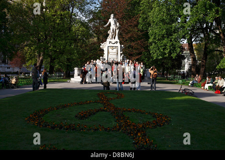 I turisti foto di gruppo intorno alla statua di Mozart Monuement nel Burggarten, Vienna Austria Foto Stock