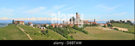 Panorama di piccole tipica città italiana con il castello medievale, hill, vigneti e montagne sullo sfondo in Piemonte, Italia. Foto Stock